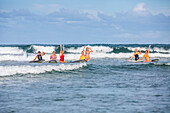 Surfer spielen und amüsieren sich mit Freunden, während sie im Wasser sind und in den Wellen am Arrawarra Beach surfen; Arrawarra, New South Wales, Australien