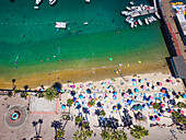 Views over California's famous island, Catalina Island, with a crowded beach and boats in Avalon harbor; Avalon, California, United States of America