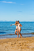 Girls in bikinis play on the golden sand beaches of the Able Tasman National Park; Tasman, New Zealand
