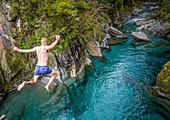 Die Blue Pools von Makarora bieten verlockend blaues Wasser zum Schwimmen. Ein Mann springt von einer Brücke ins Wasser im Mount Aspiring National Park; Makarora, Neuseeland