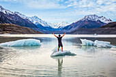 Mann steht auf einem kleinen Eisberg in der Mitte eines Gletschersees im Mount Cook National Park; Canterbury, Neuseeland.
