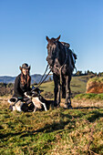 The Blue Duck lodge located in the Whanganui National Park is a working cattle farm with a focus on conservation. Travellers go to a scenic viewpoint to watch the sunrise over the rainforest. A cowgirl with her horse and dogs; Retaruke, Manawatu-Wanganui, New Zealand