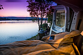 Travelers pull up alongside a lake in Bratislava to free camp for the night. A view from the bed in the back of the camper van; Bratislava, Bratislava Region, Slovakia