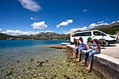 A group of friends sitting outside their camper van as they stop in Slano for an afternoon at the beach; Slano, Dubrovacko-neretvanska zupanija, Croatia