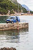 Women travelers stop for an early morning swim in the ocean after camping in their van on a road trip; Podgora, Split-Dalmatia County (Splitsko-dalmatinska zupanija), Croatia