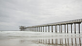 Die lange Ausdehnung des ikonischen Scripps Piers im Pazifik bei San Diego an einem grauen Tag; La Jolla, San Diego County, Kalifornien, Vereinigte Staaten von Amerika.