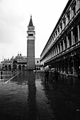 The iconic St Mark's Campanile and St Mark's Basilica in St Mark's Square with tourists sightseeing on a rainy day; Venice, Venezia, Italy
