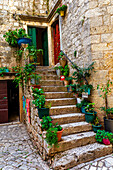 Altes Steingebäude mit von Topfpflanzen gesäumten Treppen, die zu den Eingängen der Wohnungen in der mittelalterlichen Inselstadt Trogir führen; Trogir, Kroatien