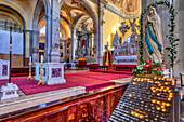 Interior of the Church of St Euphemia, showing a religious statue and candles lit for prayers and intentions with an elaborate main altar in the background; Rovinj, Istria, Croatia
