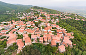 Aerial view of the historic mountainside town of Signagi with its red, clay rooftops overlooking the Greater Caucasus Mountains in Eastern Georgia; Signagi, Kakheti, Georgia