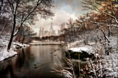 Blick auf die Stadt durch die schneebedeckten Bäume und die Uferlinie um den See im Central Park; New York City, New York, Vereinigte Staaten von Amerika.