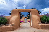 Blick durch die Lehmtore auf den Eingang zum Innenhof und die Fassade der historischen Kirche San Francisco de Asis auf dem Hauptplatz von Ranchos de Taos; Taos, New Mexico, Vereinigte Staaten von Amerika.