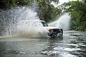 A safari vehicle splashes through a river crossing in the Costa Rican rainforest on the Osa Peninsula; Puntarenas, Costa Rica