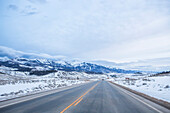 A drive down a snowy, empty highway through southern Colorado on a cloudy day; Colorado, United States of America