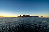 Dramatischer Blick auf Devil's Peak, Tafelberg und die Skyline von Kapstadt in der Morgendämmerung vom Meer aus; Kapstadt, Kapprovinz, Südafrika.