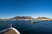 Close-up of the bow of a ship in Table Bay looking towards the Port of Cape Town and the majestic Devil's Peak,Table Mountain and Lion's Head rising above the city skyline and waterfront in the morning light from the sea; Cape Town, Cape Province, South Africa