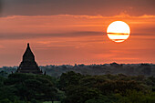 Silhouette of pagoda with the sun rising above the Plain of Bagan at dawn; Bagan, Mandalay, Myanmar (Burma)