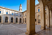 Piazza del Duomo with the Lecce Cathedral bell tower and surrounding buildings with a portico in the Historic Center of Lecce; Lecce, Puglia, Italy