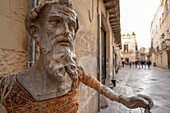 Street scene with a close-up of a paper mache (papier-mâché) figure in front of a building in the Old Town of Lecce; Lecce, Puglia, Italy