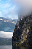 Nahaufnahme der Felswand der steilen Klippen mit Nebelwolken über dem Sieben-Schwestern-Wasserfall und spektakulärem Blick bei der Fahrt durch den 15 km langen Geirangerfjord in Sunnmore; Geirangerfjord, Stranda, Norwegen.