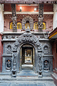 Verzierte Schnitzereien umgeben den Torbogen des Goldenen Tempels Kwa Bahal in der alten Stadt Patan oder Lalitpur, der im zwölften Jahrhundert von König Bhaskar Varman im Kathmandutal erbaut wurde; Patan (Lalitpur), Kathmandutal, Nepal.