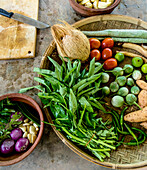 Nahaufnahme von frischem Gemüse und Zutaten auf einem Steintisch mit Schneidebrett und Messer bei einer Kochvorführung in der ländlichen Kochschule in der Nähe von Galle; Galle, Bezirk Galle, Südprovinz, Sri Lanka.