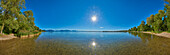 Lake Chiemsee with a sunburst in a blue sky on a sunny day with; Bavaria, Germany