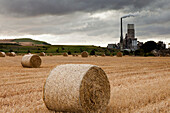 Eine Zementproduktionsanlage mit Heuballen auf einem Feld im Vordergrund; Lothian Schottland