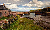 Fischreusen, ein Haus und anlegende Boote an der Küste; Cove Lothian Schottland