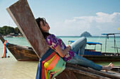 Ein Mädchen entspannt sich auf einem Boot an der Küste; Phi Phi Inseln Thailand