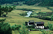 Bhutan, Fluss schlängelt sich durch Ackerland und Häuser; Paro-Tal.