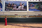 Burma (Myanmar), Bago, Shwethalyaung, Novize betrachtet gemalte Reliefs an der Wand.