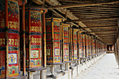 China, Xiahe, Row Of Colorful Prayer Wheels; Labrange Monastery