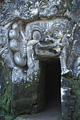 Indonesien, Bali, Goa Gajah Elefantenhöhle, Steinmetzarbeiten in der Wand, Türöffnung mit Moos bedeckt
