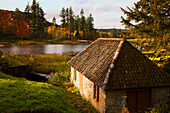 Ein Haus entlang eines Flusses im Herbst; Northumberland England
