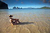 Eine Touristin im Bikini sitzt im flachen Wasser nahe El Nido und Corong Corong; Bacuit Archipelago Palawan Philippinen