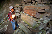 A Tour Guide Uses A Lantern To Look At The Many Coffins In The Entrance To Lumiang Burial Cave Near Sagada; Luzon Philippines