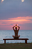 Eine Touristin macht Yoga und Dehnübungen bei Sonnenuntergang am Strand einer tropischen Insel; Koh Lanta Thailand