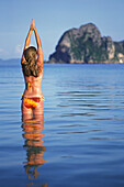 Eine Touristin im Bikini streckt sich im Sonnenschein auf der tropischen Insel Koh Ngai oder Ko Ngai bei Trang; Koh Ngai Thailand