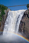 Wasserfall mit Hängebrücke oben und einem Regenbogen unten; Quebec Kanada