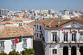 Fahnen auf der Vorderseite eines Gebäudes und ein Stadtbild mit blauem Himmel; Faro Algarve Portugal