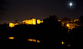 Der Vollmond leuchtet hell über einer nachts beleuchteten Stadt; Alnwick Northumberland England