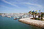 Flaggen säumen die Steinmauer im Hafen; Lagos Algarve Portugal