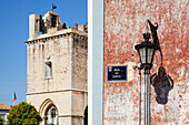 Eine Lampe an der Seite eines Gebäudes und ein Glockenturm; Faro Algarve Portugal