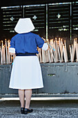 Nonne zündet eine gesegnete Kerze im Heiligtum Unserer Lieben Frau von Lourdes an; Lourdes Hautes-Pyrenäen Frankreich