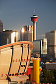 Calgary Saddledome mit dem Calgary Tower und Gebäuden im Hintergrund, die das Licht bei Sonnenaufgang reflektieren; Calgary Alberta Kanada