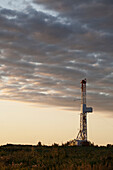 Drilling Rig With Dramatic Clouds At Sunrise; Alberta Canada
