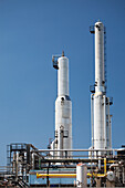 Towers Of A Refinery Against A Blue Sky; Alberta Canada