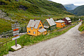Bunte Häuser entlang einer Landstraße in einem Tal; Hochland Norwegen