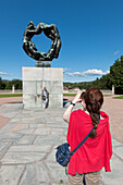 Eine Frau macht ein Foto von der Lebensrad-Skulptur im Vigeland-Skulpturenpark; Oslo, Norwegen